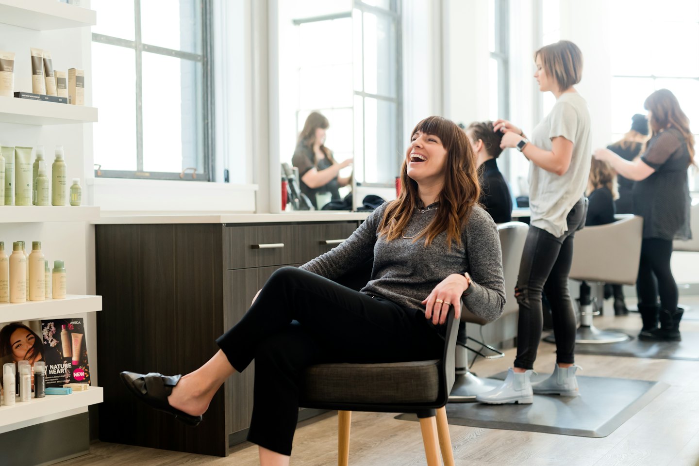 Woman laughing in a bright, modern hair salon.